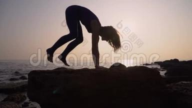 穿着紧身衣的年轻<strong>女子</strong>在令人惊叹的日出时在海面上的海滩上练习<strong>瑜伽</strong>。 健身、运动、<strong>瑜伽</strong>和健康