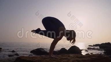 穿着紧身衣的<strong>年轻女子</strong>在令人惊叹的日出时在海面上的海滩上<strong>练习瑜伽</strong>。 健身、运动、<strong>瑜伽</strong>和健康