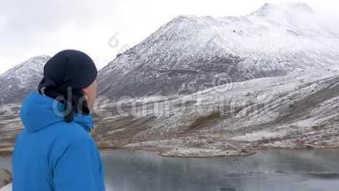 一个人站在山上的高处，欣赏着美丽的景色。 它周围有山峰和美丽的