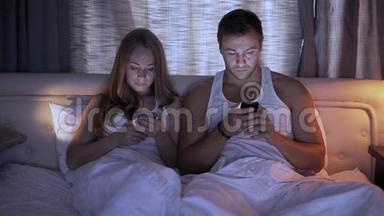酒店、科技、互动和幸福的概念-带智能手机的微笑情侣在床上