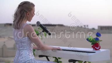<strong>优雅</strong>的年轻金发女子唱歌，在大型竞技场或圆形剧场的白色数字<strong>钢琴</strong>上演奏浪漫的音乐。 女孩