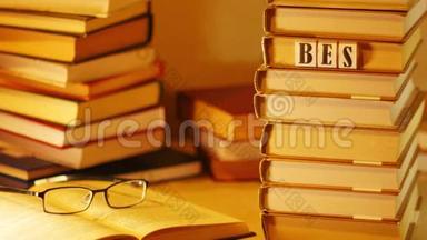 在一堆书上出现了最好的书。 在书堆的背景上用眼镜打开书。 停止运动