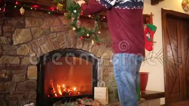穿着针织毛衣的人把圣诞花环挂在石头上，用五颜六色的闪光花环装饰着真正的壁炉