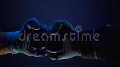一只戴着薄荷蓝色橡胶手套的手紧握成拳，<strong>因为</strong>它在漆黑的房间里的镜子里反射。 特写