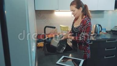 女孩在厨房砧板上洗碗。 女人在厨房做饭。 女孩在水槽里洗了一把刀