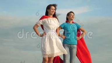 <strong>妈妈</strong>和女儿扮演<strong>超级</strong>英雄。 两个穿着<strong>超级</strong>英雄红色斗篷的女孩站在蓝天上，风吹起了一阵