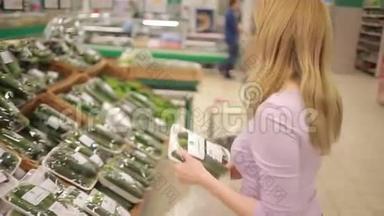 一个女人在超市的<strong>蔬菜货架</strong>上买<strong>蔬菜</strong>。 黄瓜