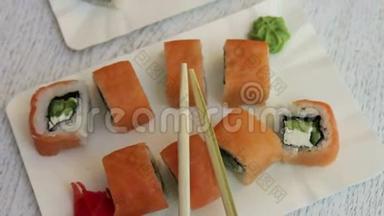 新鲜美味的寿司，里面有三文鱼、生姜、奶酪芥末和白盘子上的木棍
