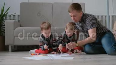 家里的爸爸和两个双胞胎兄弟一起画记号笔，把毛笔放在地板上。