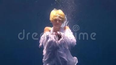 年轻女孩模特自由潜水员水下白色天使服装姿势在红海。