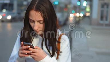 夜间街道上移动汽车背景模糊的青年女子手机短信手持镜头