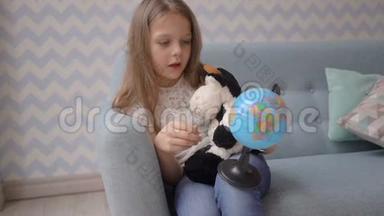 可爱的女孩在家里坐在<strong>沙发</strong>上拿着一个小地球仪，旋转着