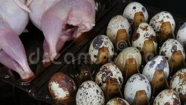 新鲜的鹌鹑肉放在一个塑料棕色托盘旁边的鹌鹑蛋黑色背景。 女人的手把鸡蛋从
