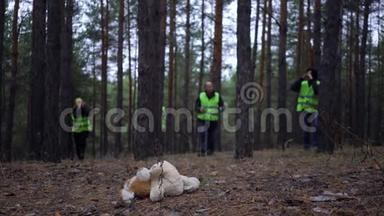一群身穿绿色背心的志愿者在松林中寻找失踪人员