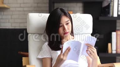 美丽的<strong>肖像</strong>，年轻的亚洲女人放松坐在客厅<strong>看书</strong>在家，女孩学习文学。