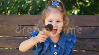 小女孩在阳光明媚的夏天在公园里吃冰淇淋和巧克力。 婴儿特写肖像