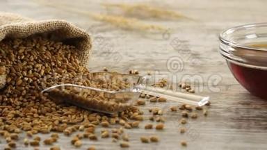 一堆小麦，蜂蜜和新鲜的面包放在乡村的木桌上。 乡村早餐。