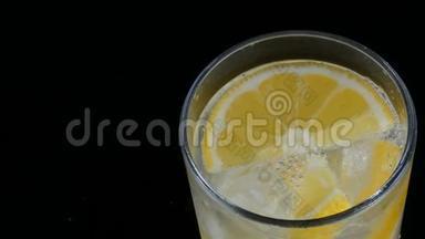 用冰块和冷苏打切好的柠檬在一个长长的杯子里，黑色背景的近景。 新鲜柠檬酱