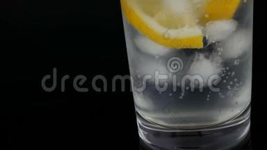 用冰块和冷苏打切好的柠檬在一个长长的杯子里，黑色背景的<strong>近景</strong>。 新鲜柠檬酱