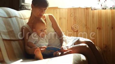 妈妈和她两岁的小<strong>男孩</strong>坐在阳光明媚的房间里的扶手椅上<strong>看书</strong>