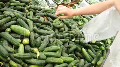 一个女人在蔬菜货架上的超市里买蔬菜和水果。 男人选择黄瓜。 慢动作
