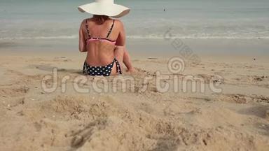 穿比基尼、戴太阳帽的女人在海边晒日光浴的后景