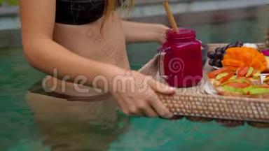 一位年轻的女游客在<strong>私人</strong>游泳池的一张漂浮的桌子上有自己的<strong>私人</strong>早餐。 热带海滩