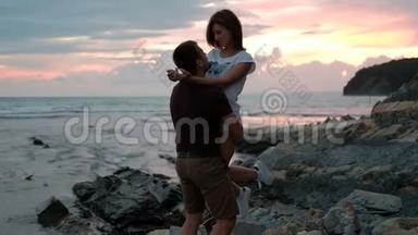 年轻男子抱着女<strong>人</strong>，站在海滩上的夏天晚上户外。