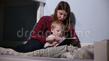 儿子和母亲在床上玩触摸垫游戏的特写镜头。 业余娱乐。