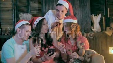 无忧无虑的青少年朋友庆祝圣诞节附近装饰圣诞节观看视频智能手机。