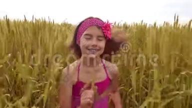 快乐奔跑的孩子户外女孩在麦田的阳光下。 女孩穿过黄色的麦田