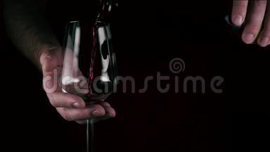 一个人把酒倒在黑色背景上的杯子里。 慢动作