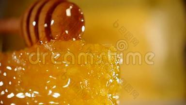 蜂蜜滴在蜂窝上，黄色背景。 从木制蜂蜜中浸泡出厚的有机蜂蜜