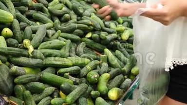 一个女人在蔬菜货架上的<strong>超市</strong>里买蔬菜和<strong>水果</strong>。 男人选择黄瓜。 慢动作