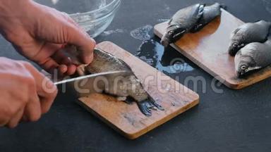 人从木板上的鳞片上清洁鲤<strong>鱼</strong>。 特写双手。 做<strong>一条鱼</strong>。