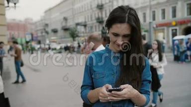 现代技术。 美丽的黑发年轻女子穿着牛仔裙，在繁忙的街道上使用她的智能手机。 慢节奏