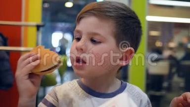 小男孩在儿童餐厅吃饭时胃口大开，儿童晚餐吃食物，午餐吃薯条和汉堡
