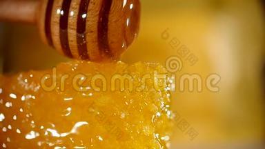 蜂蜜滴在蜂窝上，黄色背景。 从木制蜂蜜中浸泡出厚的有机蜂蜜