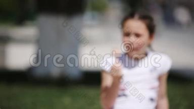在阳光明媚的夏日，可爱的小女孩在公园里吃冰淇淋。