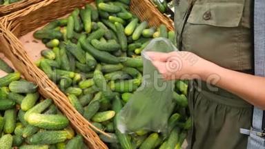 一个女人在蔬菜货架上的超市里买蔬菜和水果。 男人选择黄瓜。 慢动作，4k