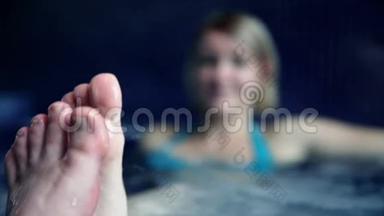 在泳池里，穿着蓝色比基尼的年轻女子摸着脚