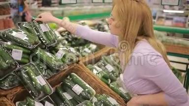一个女人在超市的<strong>蔬菜货架</strong>上买<strong>蔬菜</strong>。 黄瓜