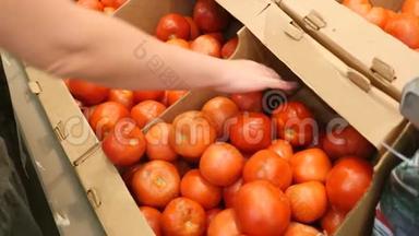 一个女人在蔬菜货架上的超市里买蔬菜和水果。 男人从腐烂的蔬菜中选择西红柿