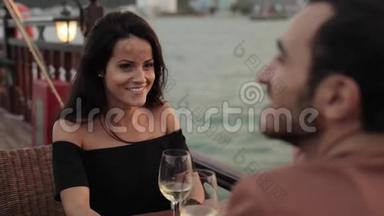 年轻漂亮的夫妇一起坐在游船甲板上端着酒杯