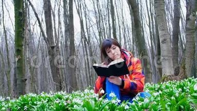 一个漂亮聪明的女孩正在春天的森林里读一本有趣的书，里面满是<strong>朵朵</strong>的雪花