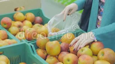 超市里的女人来到水果柜台。 她选择把苹果放进塑料袋里