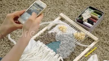 一个女人在织布机上织着一件由纱线制成的美丽刺绣，在一<strong>家家</strong>庭工作室里，电话里有照片