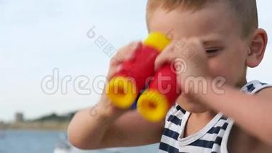 穿着条纹衬衫的可爱小男孩透过双筒望远镜看海