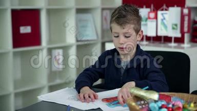 小男孩在幼儿园用蓝色铅笔画画