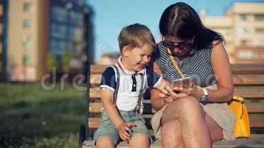 妈妈和她的小儿子在公园里笑<strong>着看着</strong>智能<strong>手机</strong>上的东西